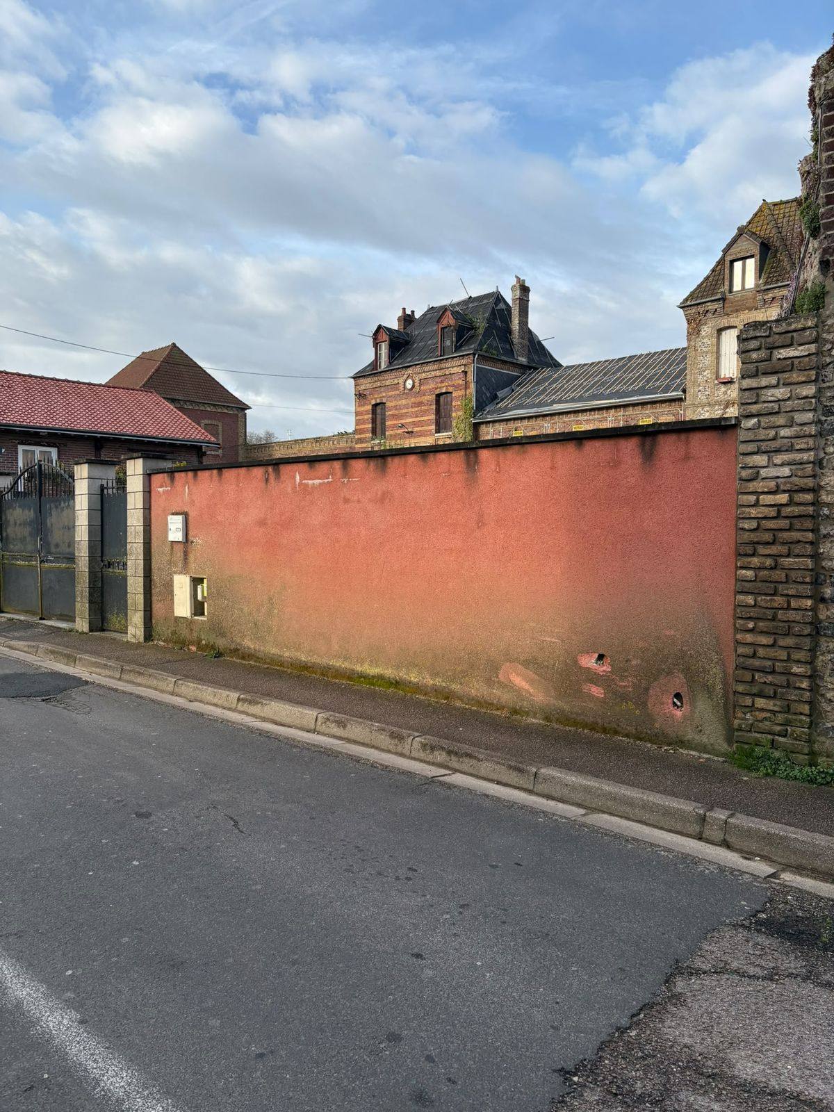 Long mur de clôture le long de la rue, avant travaux