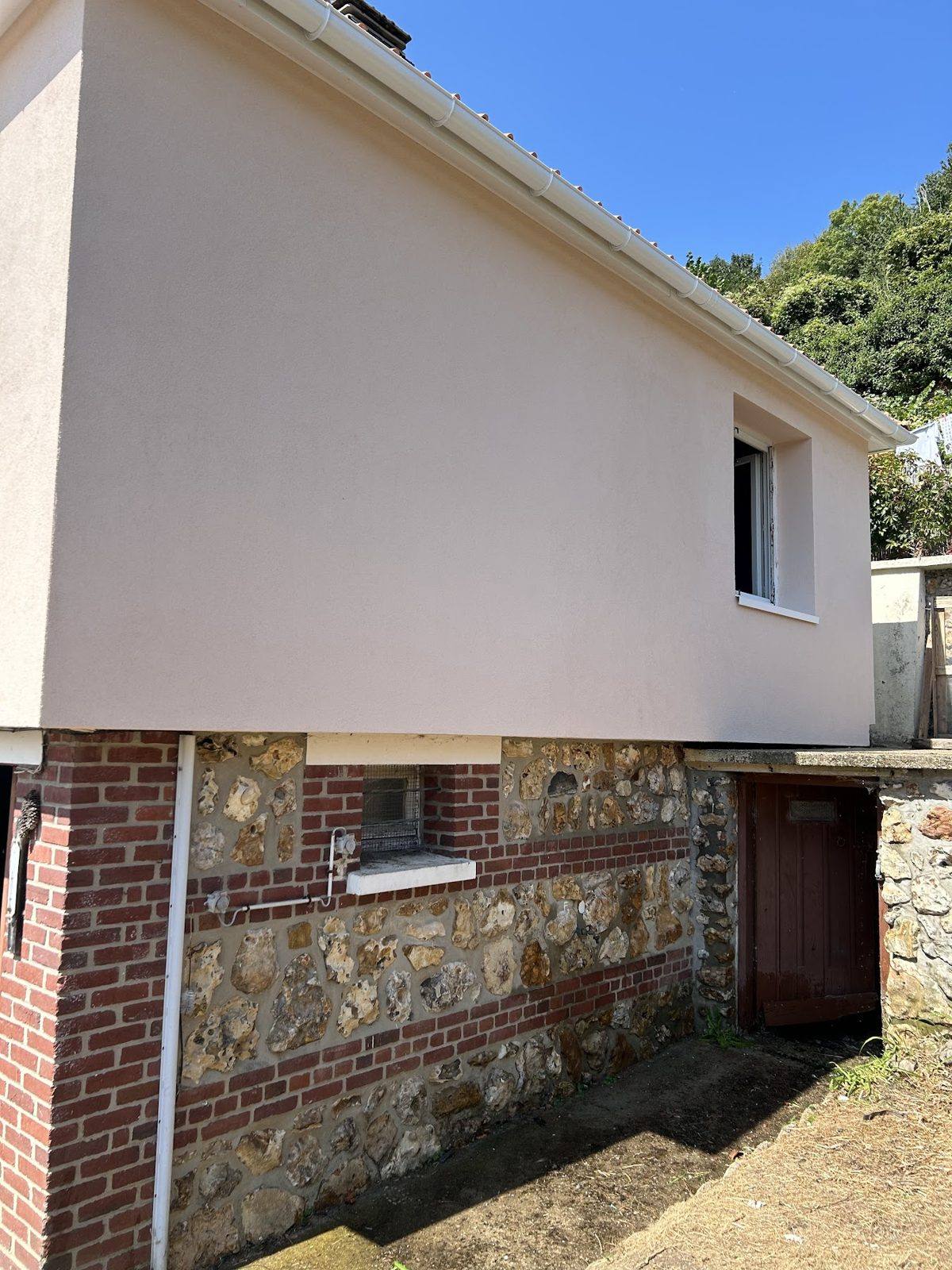 Façade enduite au-dessus d’un soubassement en silex