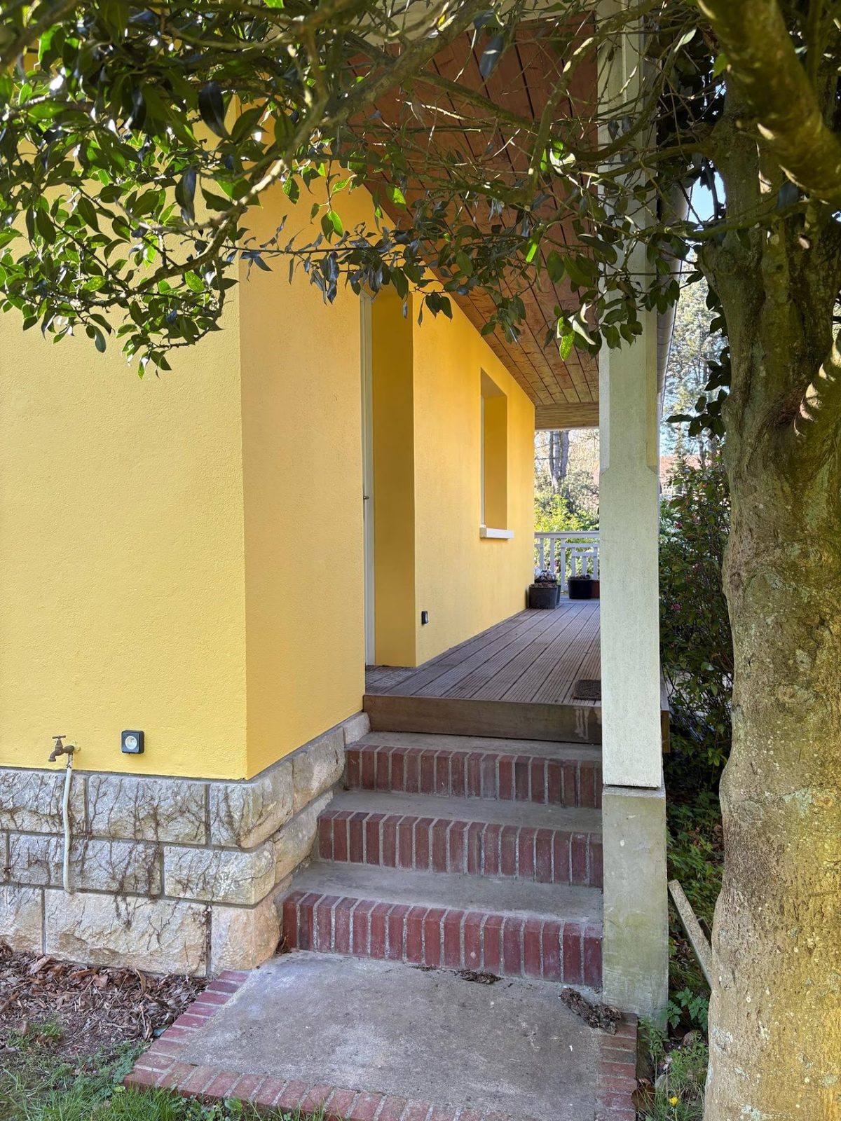 Façade jaune enduite au-dessus d’un soubassement en pierre